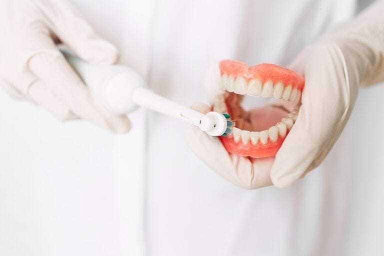 Oral hygiene. Dentist shows how to brush your teeth. Dental prosthesis in the hands of the doctor